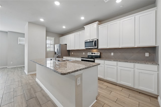 2832 Baneberry Ln, Mesquite, TX 75150 - kitchen with appliances with stainless steel finishes, a sink, a kitchen island with sink, wood finish floors, and decorative backsplash