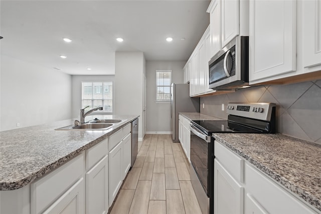 2832 Baneberry Ln, Mesquite, TX 75150 - kitchen featuring appliances with stainless steel finishes, a sink, white cabinetry, baseboards, and tasteful backsplash
