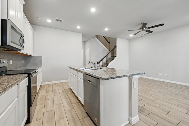 2832 Baneberry Ln, Mesquite, TX 75150 - kitchen with stainless steel appliances, ceiling fan, wood tiled floors, a sink, and a kitchen island with sink