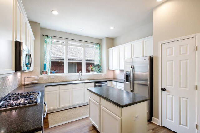 9121 Rio Blanco Dr, Frisco, TX 75033 - kitchen featuring appliances with stainless steel finishes, a sink, decorative backsplash, wood finished floors, and recessed lighting