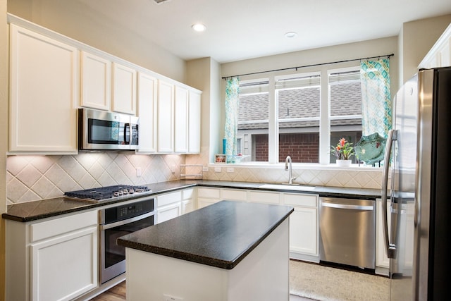 9121 Rio Blanco Dr, Frisco, TX 75033 - kitchen featuring stainless steel appliances, a sink, white cabinetry, dark countertops, and decorative backsplash