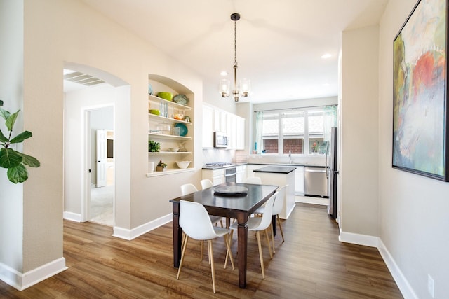 9121 Rio Blanco Dr, Frisco, TX 75033 - dining area featuring a chandelier, dark wood-style floors, recessed lighting, arched walkways, and baseboards