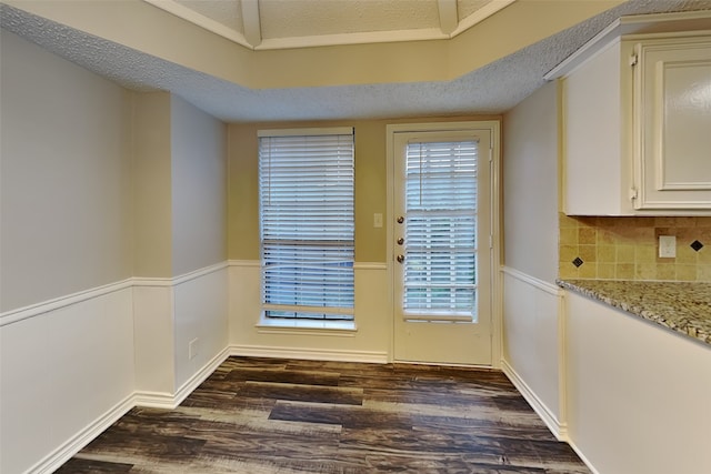 2800 Glen Forest Ln, Plano, TX 75023 - unfurnished dining area featuring dark wood-type flooring, a textured ceiling, and wainscoting