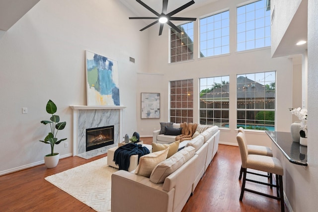 2445 Sky Harbor Dr, Plano, TX 75025 - living room featuring ceiling fan, a high end fireplace, wood finished floors, and a towering ceiling