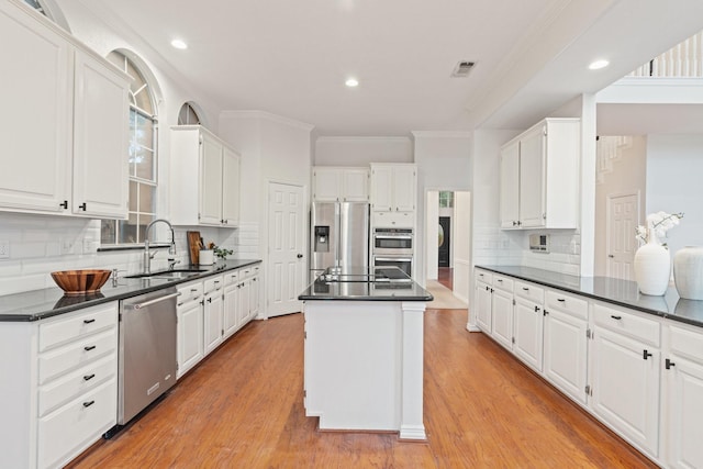 2445 Sky Harbor Dr, Plano, TX 75025 - kitchen with appliances with stainless steel finishes, a sink, dark countertops, a kitchen island, and white cabinets