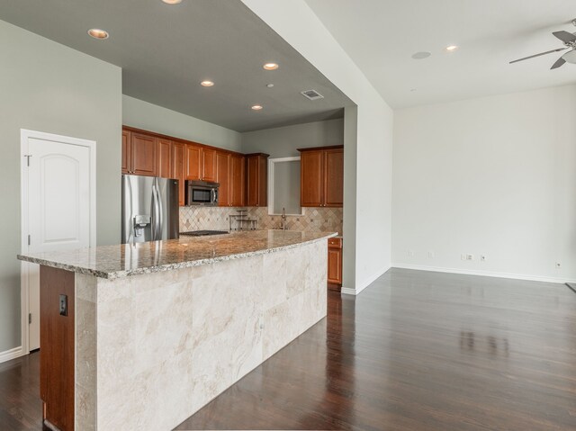 13900 Noel Rd Unit 2, Dallas, TX 75240 - kitchen with stainless steel appliances, dark wood finished floors, a ceiling fan, decorative backsplash, and light stone countertops