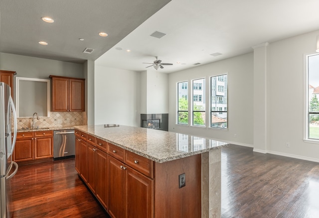 13900 Noel Rd Unit 2, Dallas, TX 75240 - kitchen with appliances with stainless steel finishes, brown cabinets, dark wood-style flooring, a center island, and healthy amount of natural light