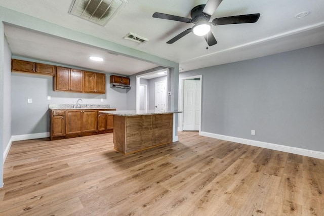 2238 Macon St, Dallas, TX 75215 - kitchen featuring brown cabinetry, light wood-type flooring, baseboards, and a sink