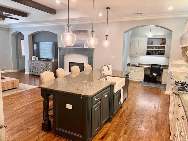 3706 Plum Vista Pl, Arlington, TX 76005 - kitchen featuring a sink, a breakfast bar, wood finished floors, open floor plan, and crown molding