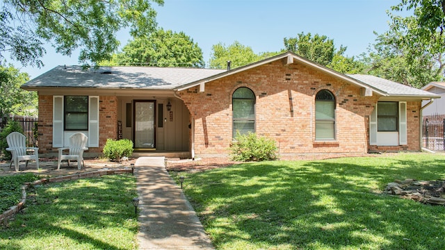 ranch-style house featuring brick siding, a shingled roof, and a porch