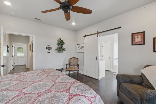 bedroom with a barn door, recessed lighting, concrete floors, baseboards, and ensuite bath