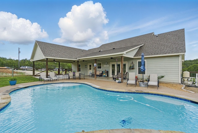 swimming pool with ceiling fan, a patio area, and french doors
