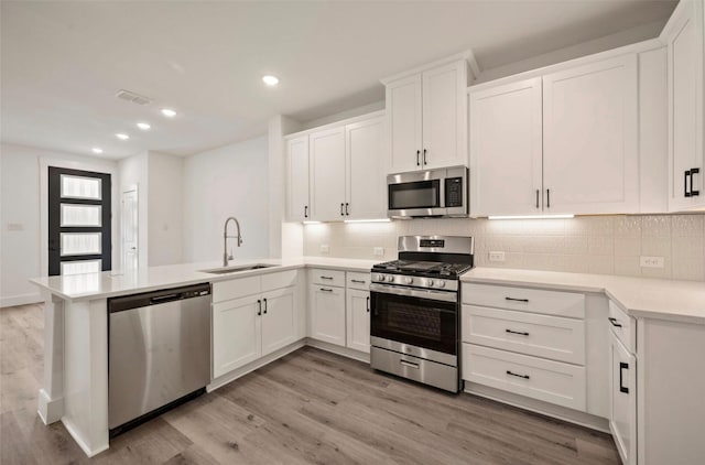 4702 Smokey Quartz Ln, Arlington, TX 76005 - kitchen featuring appliances with stainless steel finishes, a sink, a peninsula, light wood finished floors, and recessed lighting