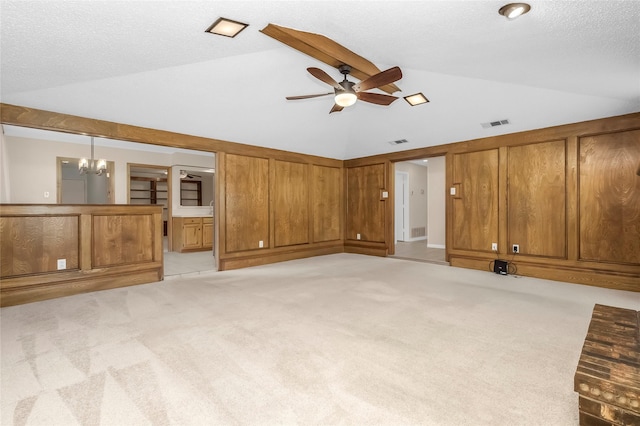 unfurnished living room with ceiling fan, light colored carpet, a chandelier, and high vaulted ceiling