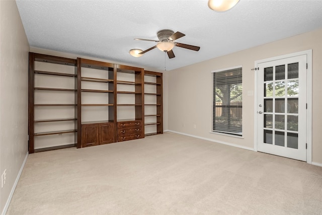 spare room featuring a ceiling fan, light colored carpet, baseboards, and a textured ceiling
