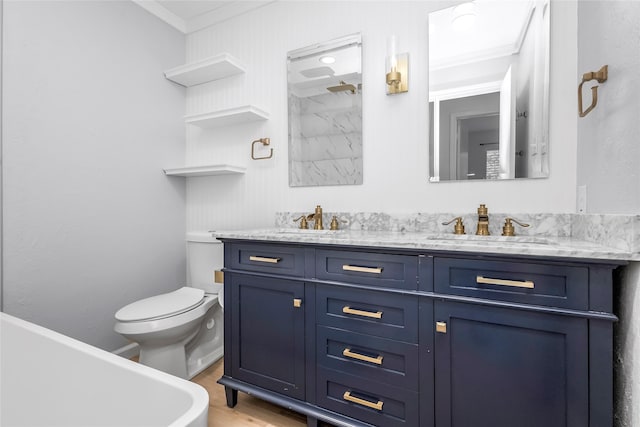 bathroom featuring ornamental molding, toilet, wood finished floors, double vanity, and a freestanding bath