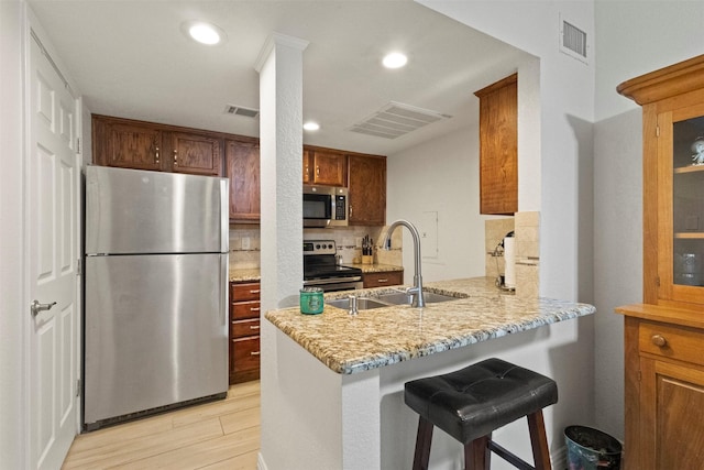 449 Harris St Unit 102D, Coppell, TX 75019 - kitchen with stainless steel appliances, a sink, decorative backsplash, a peninsula, and light stone countertops