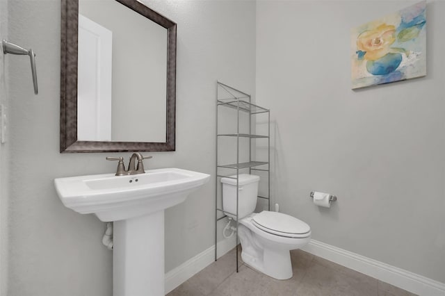 bathroom with baseboards, toilet, and tile patterned flooring