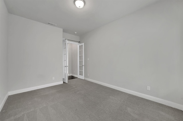 carpeted empty room featuring french doors and baseboards