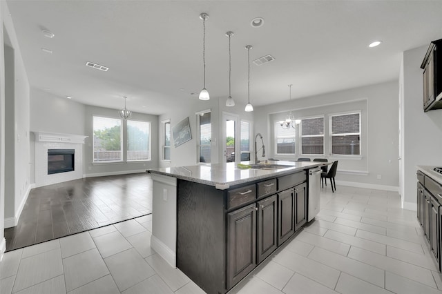 kitchen with a sink, a chandelier, a glass covered fireplace, baseboards, and recessed lighting