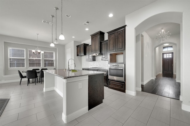 kitchen with oven, a chandelier, a sink, arched walkways, and recessed lighting