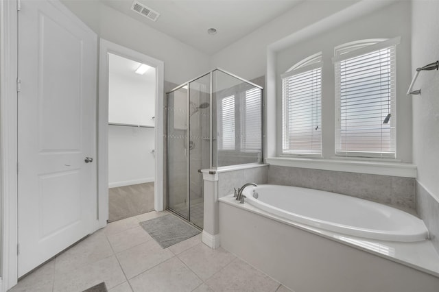 full bath featuring a stall shower, a bath, tile patterned flooring, and a walk in closet