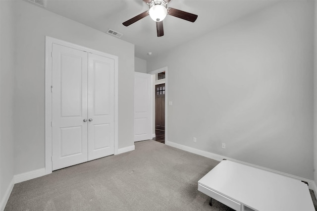 unfurnished bedroom with carpet, a closet, baseboards, and ceiling fan