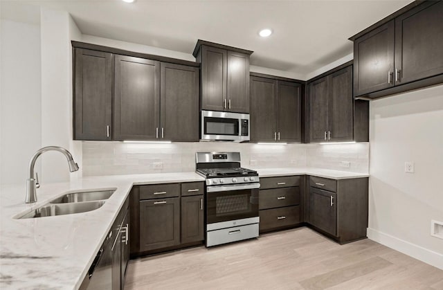 4732 Smokey Quartz Ln, Arlington, TX 76005 - kitchen featuring appliances with stainless steel finishes, a sink, light stone countertops, light wood-style flooring, and baseboards