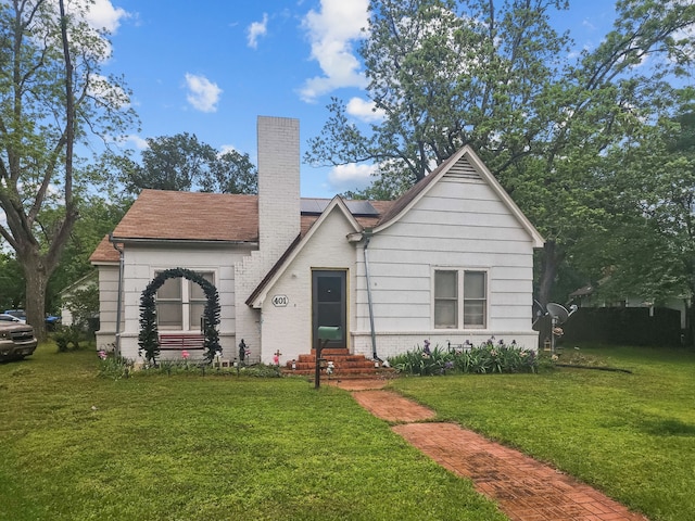 401 S 9th Ave, Teague, TX 75860 - view of front of home featuring a front yard, a chimney, roof mounted solar panels, brick siding, and entry steps