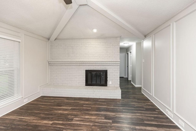 1017 Westminster Ln, Garland, TX 75040 - unfurnished living room with a decorative wall, a textured ceiling, beamed ceiling, wood finished floors, and a fireplace