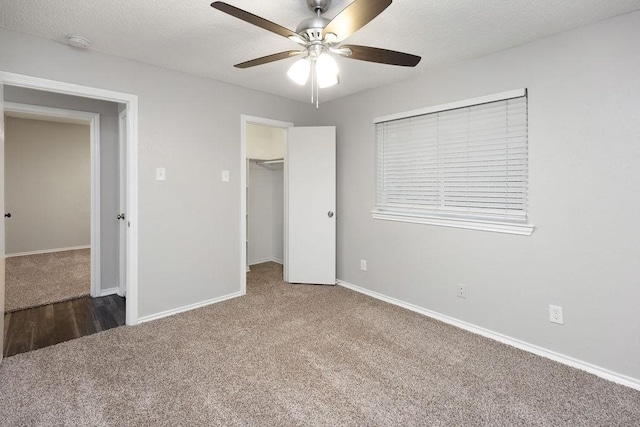 1017 Westminster Ln, Garland, TX 75040 - unfurnished bedroom with carpet flooring, baseboards, a walk in closet, a closet, and a textured ceiling