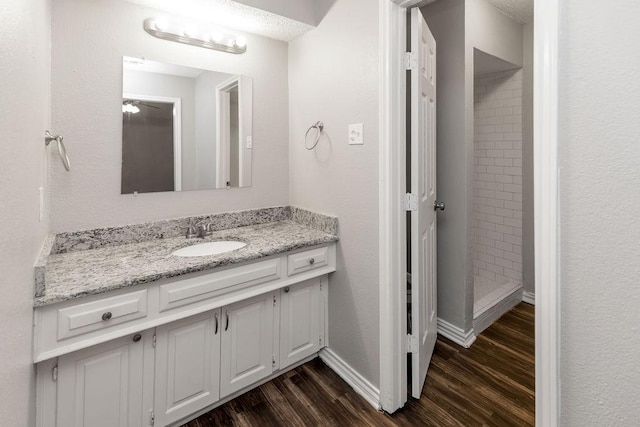 1017 Westminster Ln, Garland, TX 75040 - bathroom with wood finished floors, a stall shower, vanity, and baseboards