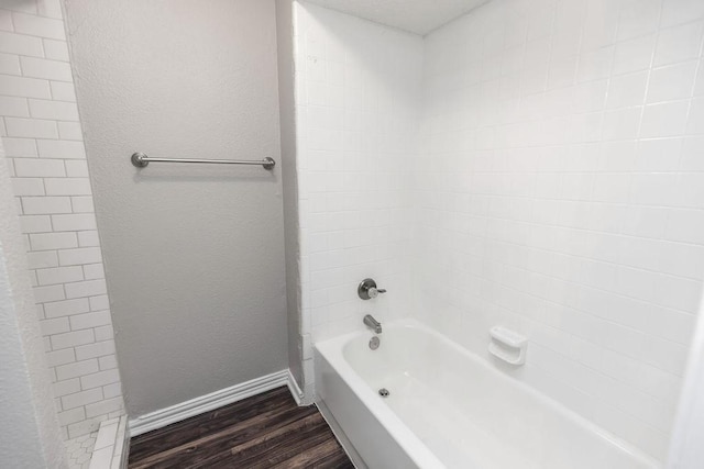 1017 Westminster Ln, Garland, TX 75040 - bathroom with wood finished floors, baseboards, shower / washtub combination, and a textured wall