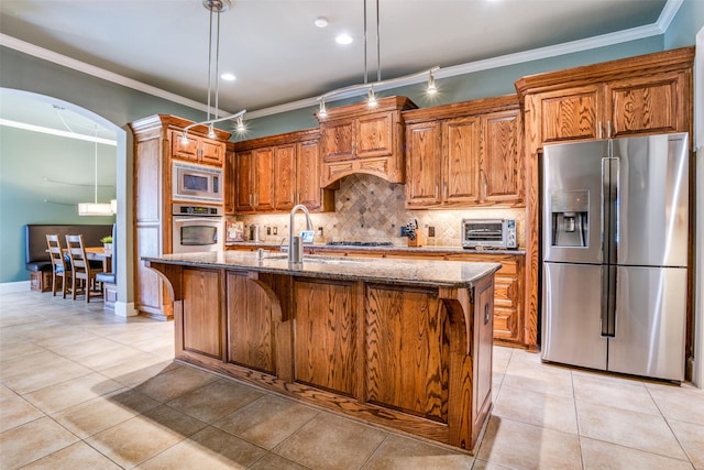 1615 San Andres Dr, Frisco, TX 75033 - kitchen with stainless steel appliances, a sink, dark stone counters, backsplash, and brown cabinetry
