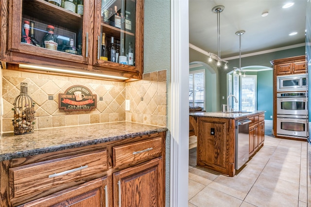 1615 San Andres Dr, Frisco, TX 75033 - kitchen with a sink, appliances with stainless steel finishes, ornamental molding, arched walkways, and brown cabinets