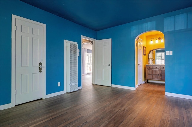 1108 W Jessamine St, Fort Worth, TX 76110 - unfurnished bedroom with a heating unit, arched walkways, wood finished floors, and baseboards