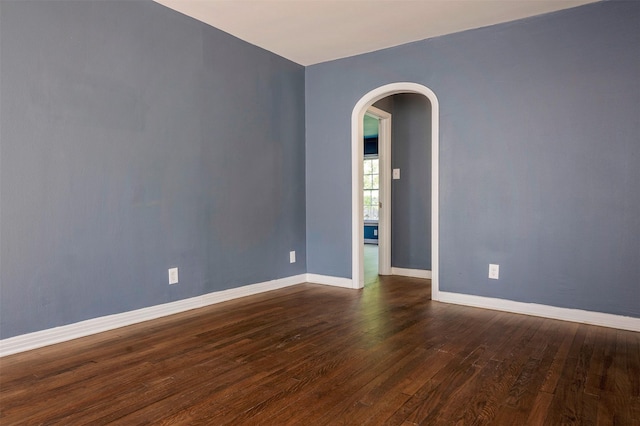 1108 W Jessamine St, Fort Worth, TX 76110 - empty room featuring arched walkways, dark wood finished floors, and baseboards