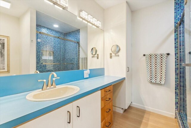 3020 N 43rd St, Waco, TX 76710 - full bathroom with a stall shower, wood finished floors, vanity, and baseboards