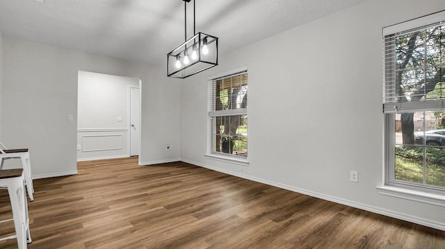 unfurnished dining area with wood finished floors and baseboards