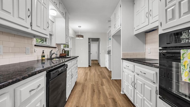 kitchen with black appliances, a sink, backsplash, and white cabinetry