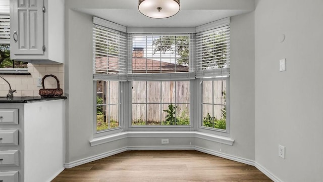 unfurnished dining area featuring healthy amount of natural light, wood finished floors, and baseboards