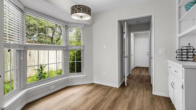 unfurnished dining area with baseboards and wood finished floors
