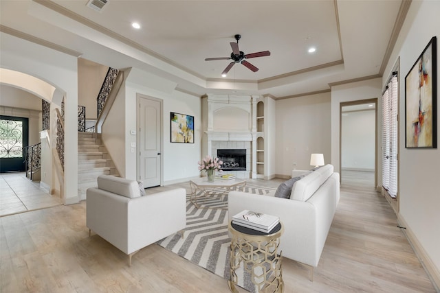 2137 Langdon Dr, Frisco, TX 75033 - living area with a tray ceiling, ceiling fan, light wood-style flooring, arched walkways, and ornamental molding