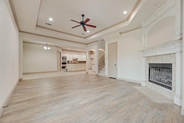2137 Langdon Dr, Frisco, TX 75033 - unfurnished living room with a raised ceiling, a tile fireplace, ceiling fan, stairs, and crown molding