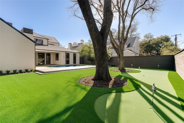 fenced backyard with an area to practice putting
