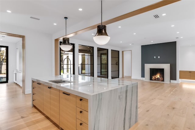 kitchen with light brown cabinetry, modern cabinets, light wood-type flooring, light stone counters, and recessed lighting