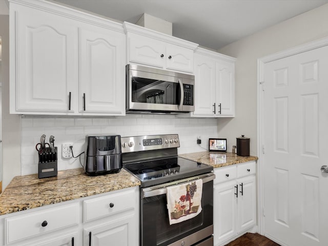 kitchen featuring appliances with stainless steel finishes, tasteful backsplash, white cabinetry, and light stone countertops