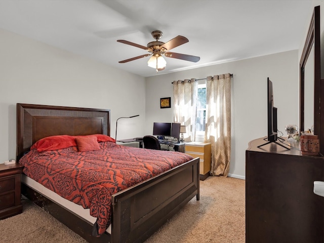bedroom featuring light colored carpet, baseboards, ceiling fan, and a desk