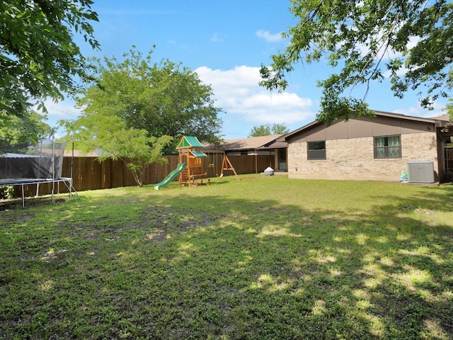 view of yard featuring a trampoline, a playground, and central air condition unit