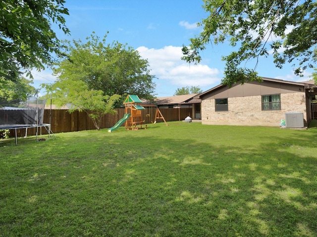 view of yard with a trampoline, a playground, and central air condition unit